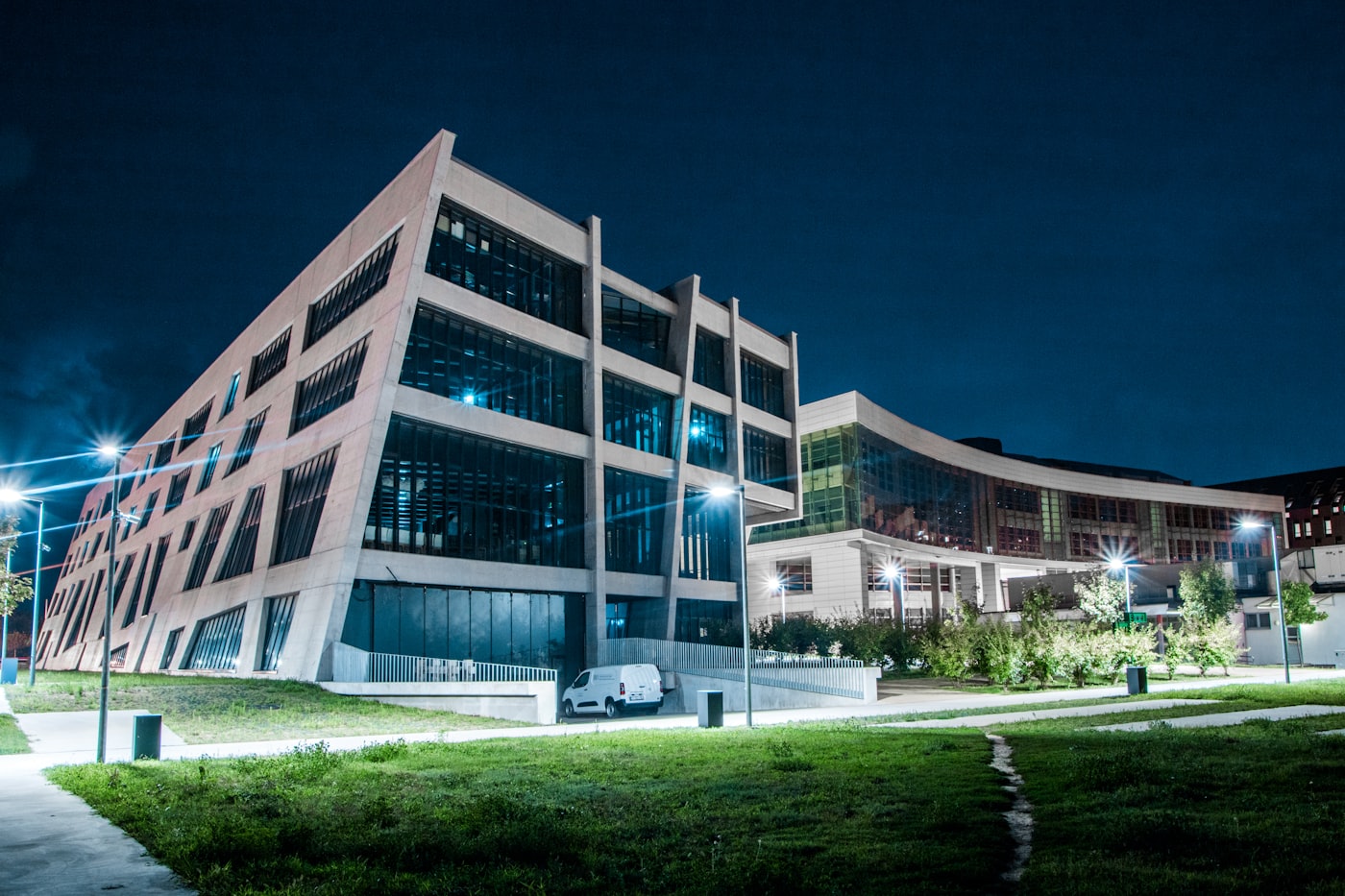 Edificio académico de vidrio iluminado al anochecer