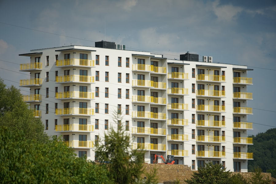 Edificio de vivienda blanco con balcones amarillos entre árboles